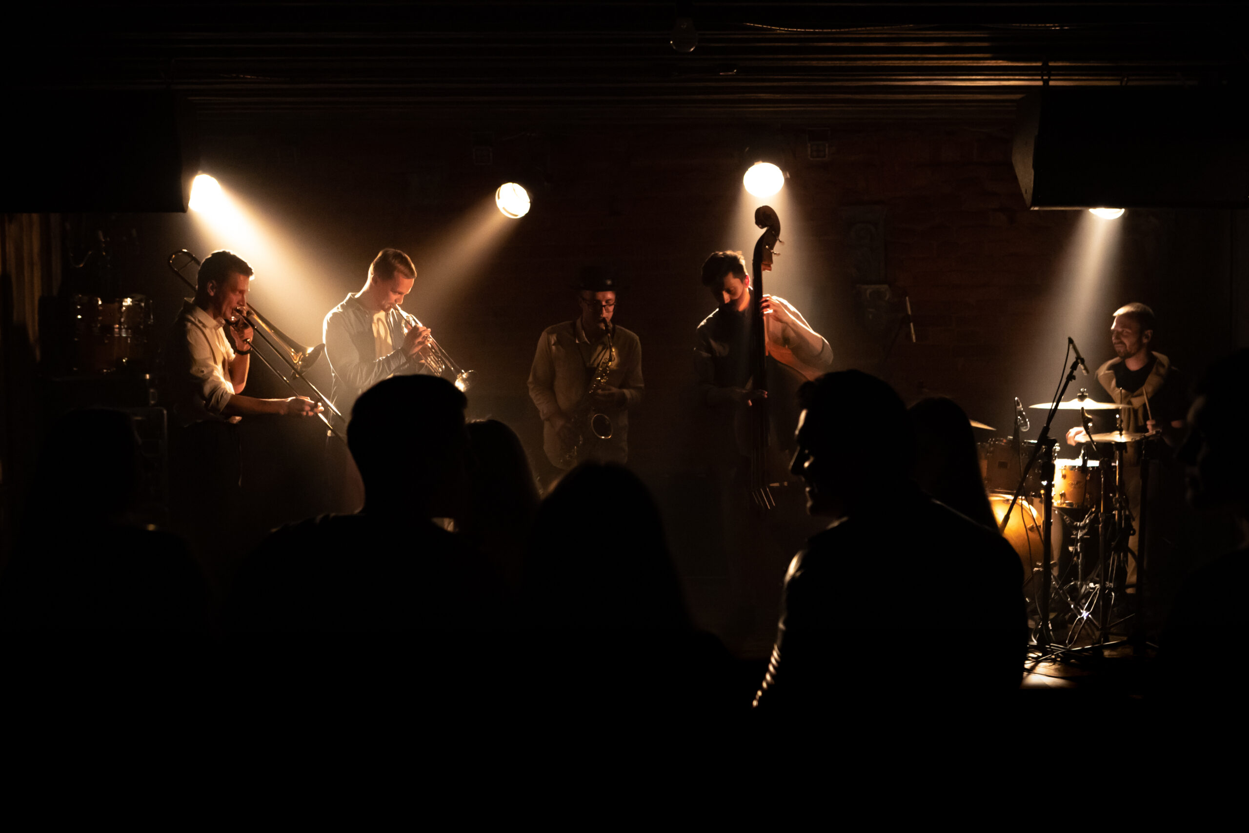 WIDE People dancing during concert of a modern jazz band playing on a stage of a small crowded venue